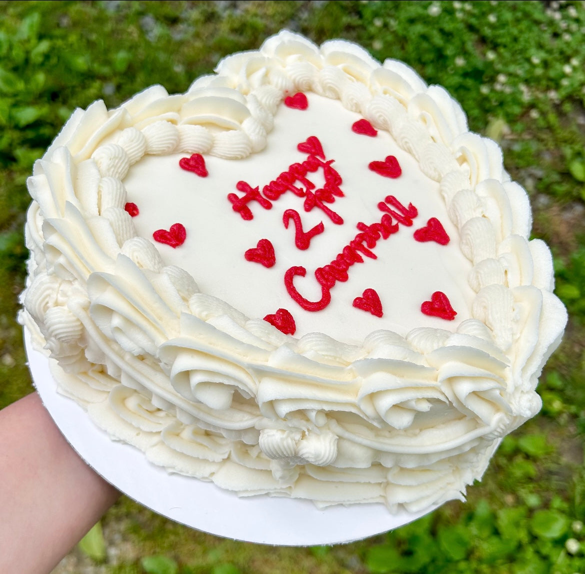 Heart-shaped cake with white frosting and 'Happy 21st Campbell' text and red hearts