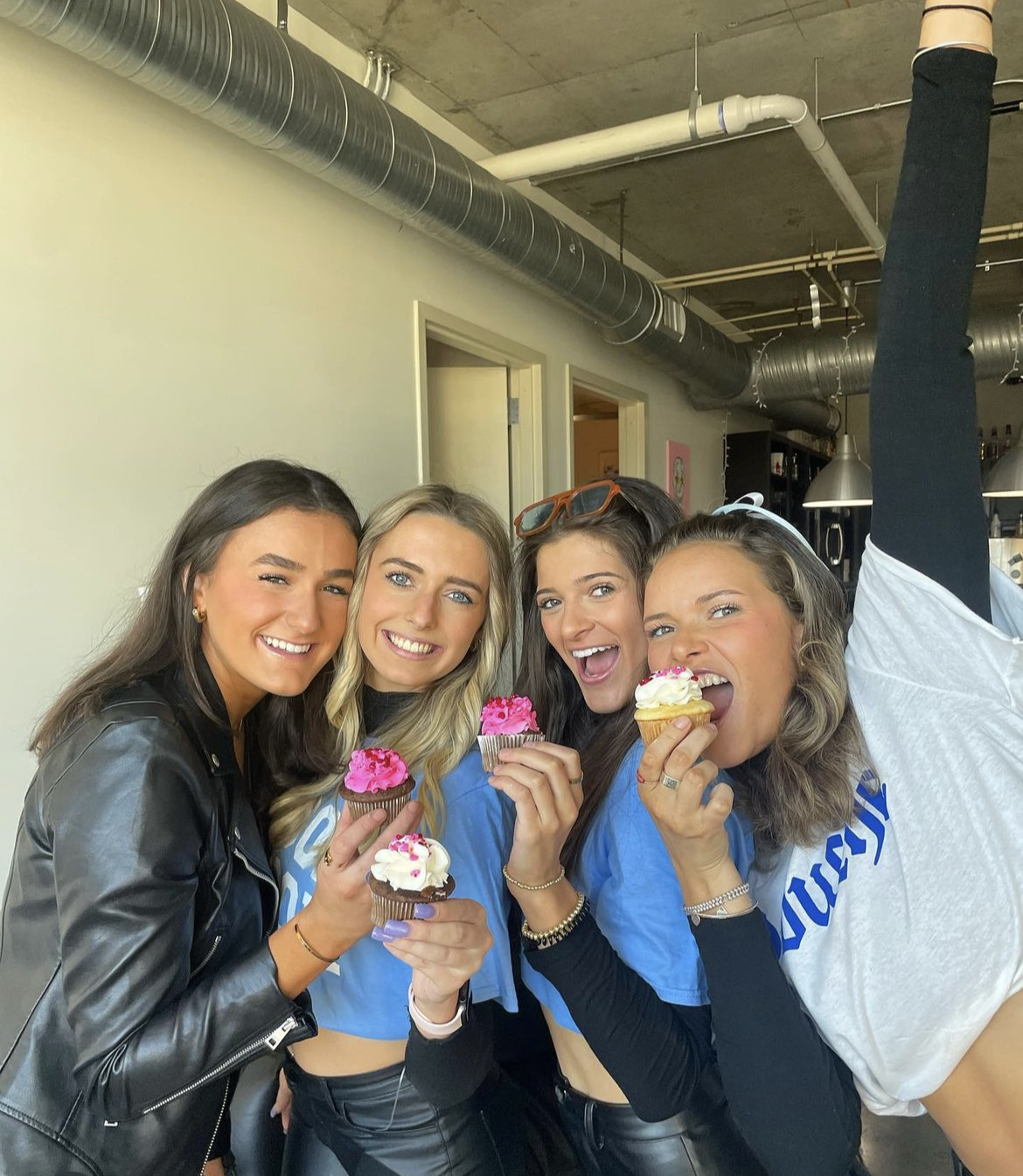 Four UNC students holding cupcakes and smiling.