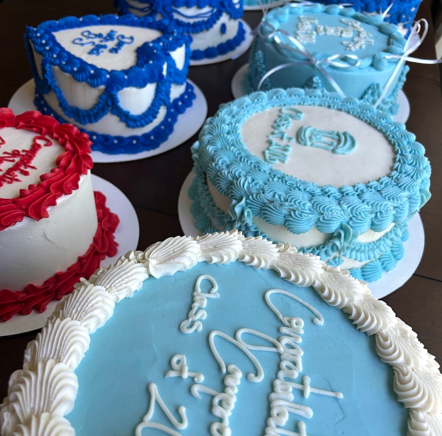 Collection of decorated graduation cakes with blue, white, and red icing.