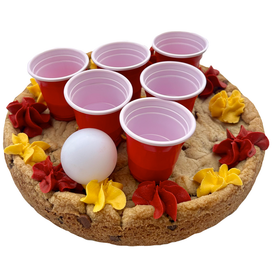 Maroon and gold cookie pong cake with mini red cups, ping pong ball, and maroon and gold frosting.