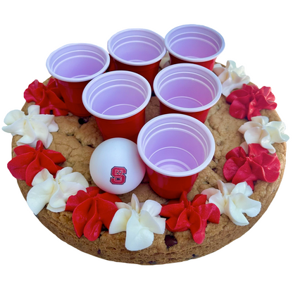 Red cookie pong cake with mini red cups, ping pong ball, and red and white frosting.