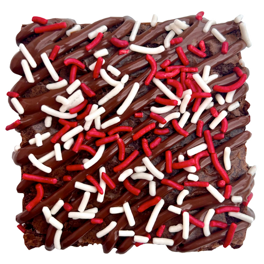 Red sprinkle brownie with chocolate drizzle and white and red sprinkles.