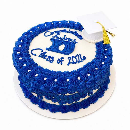 Royal blue and white cake with 'Congratulations Class of 2026' text with a graduation cap topper.