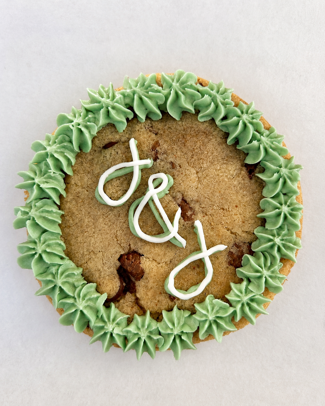 Cookie with green icing and white 'J&J' initials
